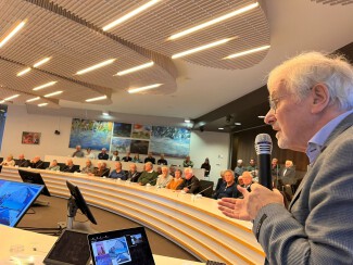 Foto van Arend Jan Heideman die de mensen in de zaal toespreekt