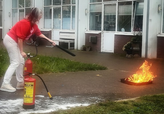 Foto van een medewerker die een brandje blust voor de BHV cursus